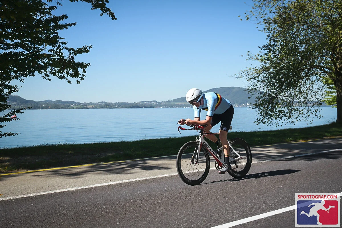 Norbert Endres auf dem Zeitfahrrad an der Uferstraße, links und rechts Bäume, dahinter der Attersee und die Hügel des Gegenufers